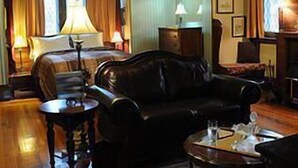 Ein gemütliches Hotelzimmer mit einem großen Bett, einem Ledersofa, einem kleinen Tisch und einer Kristallleuchter.