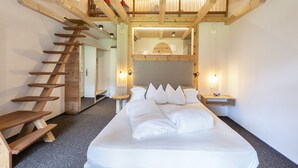 Een slaapkamer met een groot bed, een houten trap en uitzicht op een balkon.