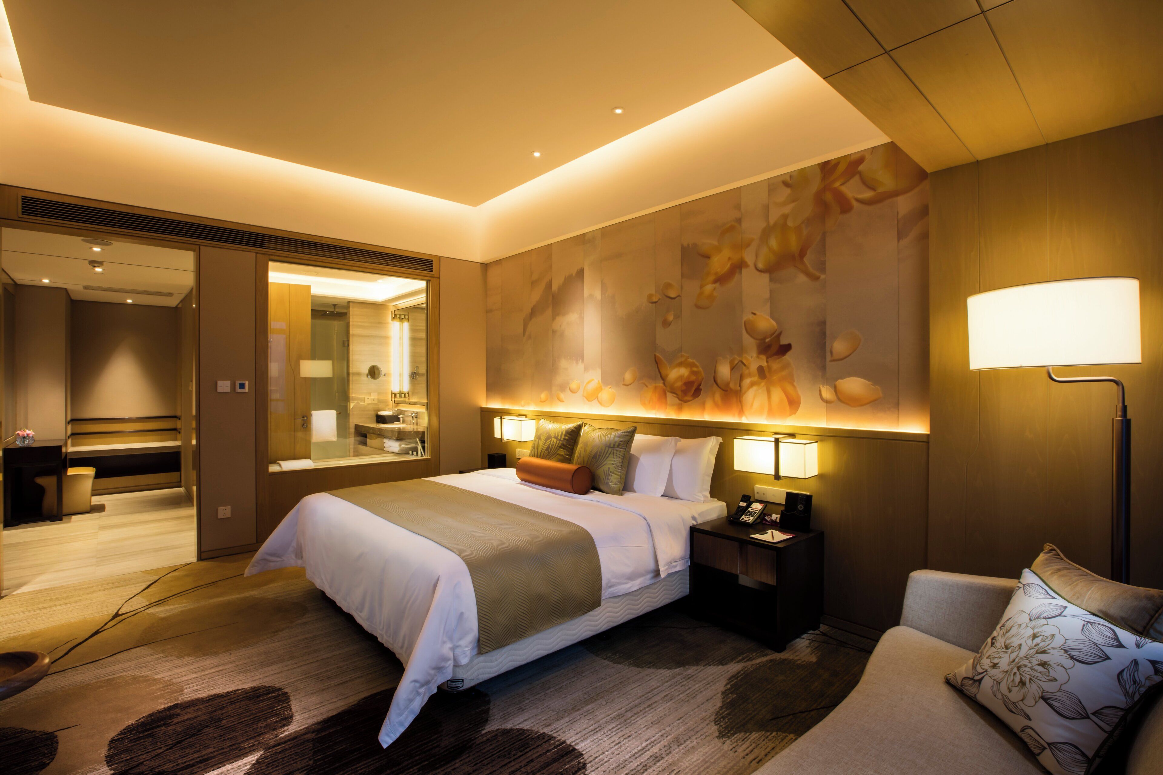 A hotel room with a large bed, bedside tables, a desk, a chair, and a large wall mural.