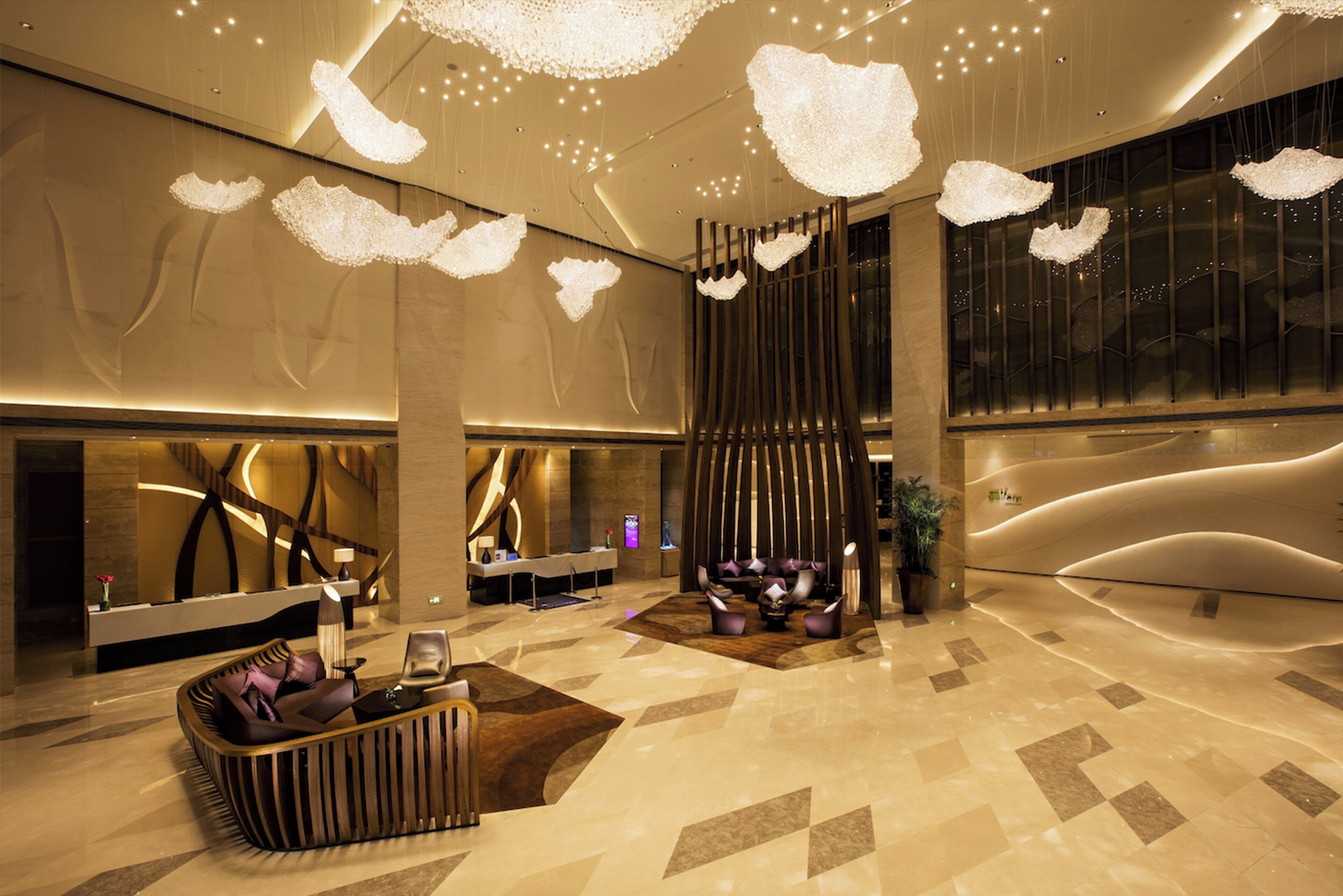 A modern lobby with a reception desk, seating area, and decorative lighting.