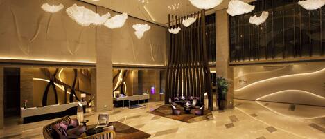 A modern lobby with a reception desk, seating area, and decorative lighting.