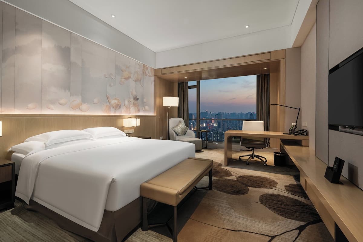 Ett modernt hotellrum med en stor säng, ett skrivbord, en stol och en TV.
