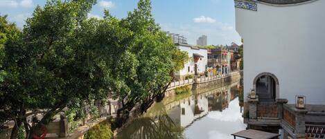 A traditional building with a curved roof and a stone bridge over a calm river.