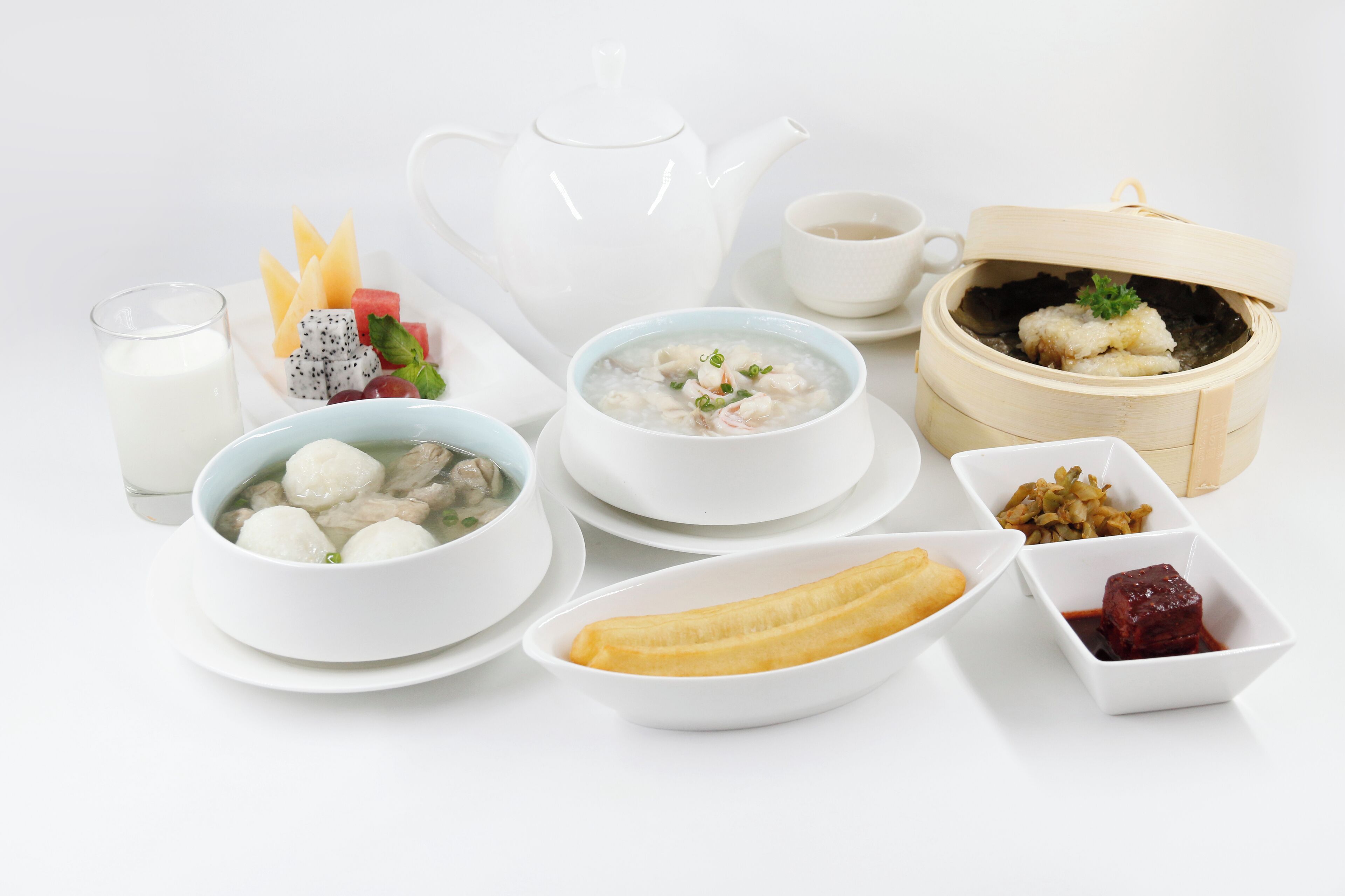 A table set with various dishes including soup, dumplings, and fruit.