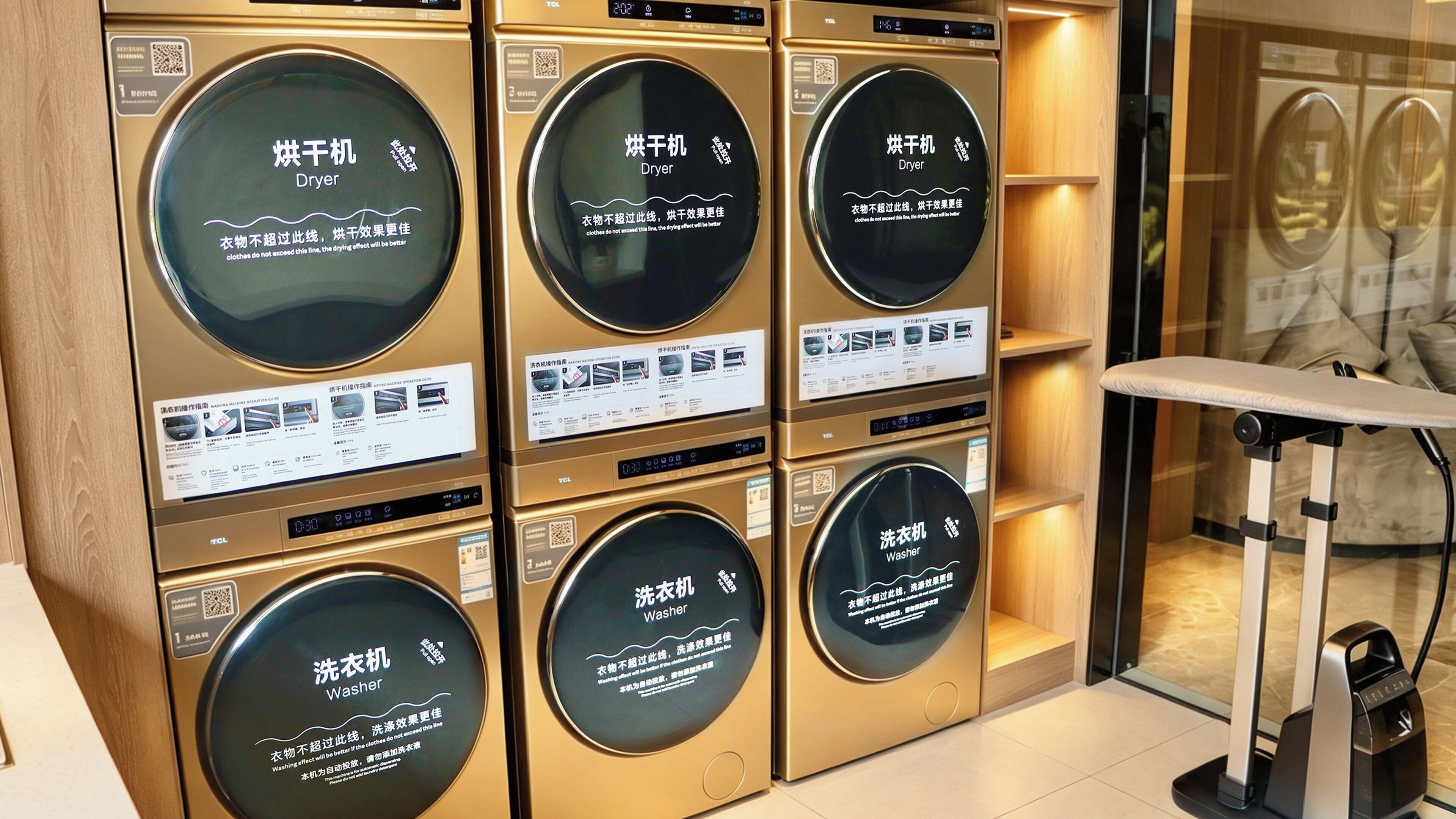A row of wall-mounted washing machines and dryers with instructional labels.