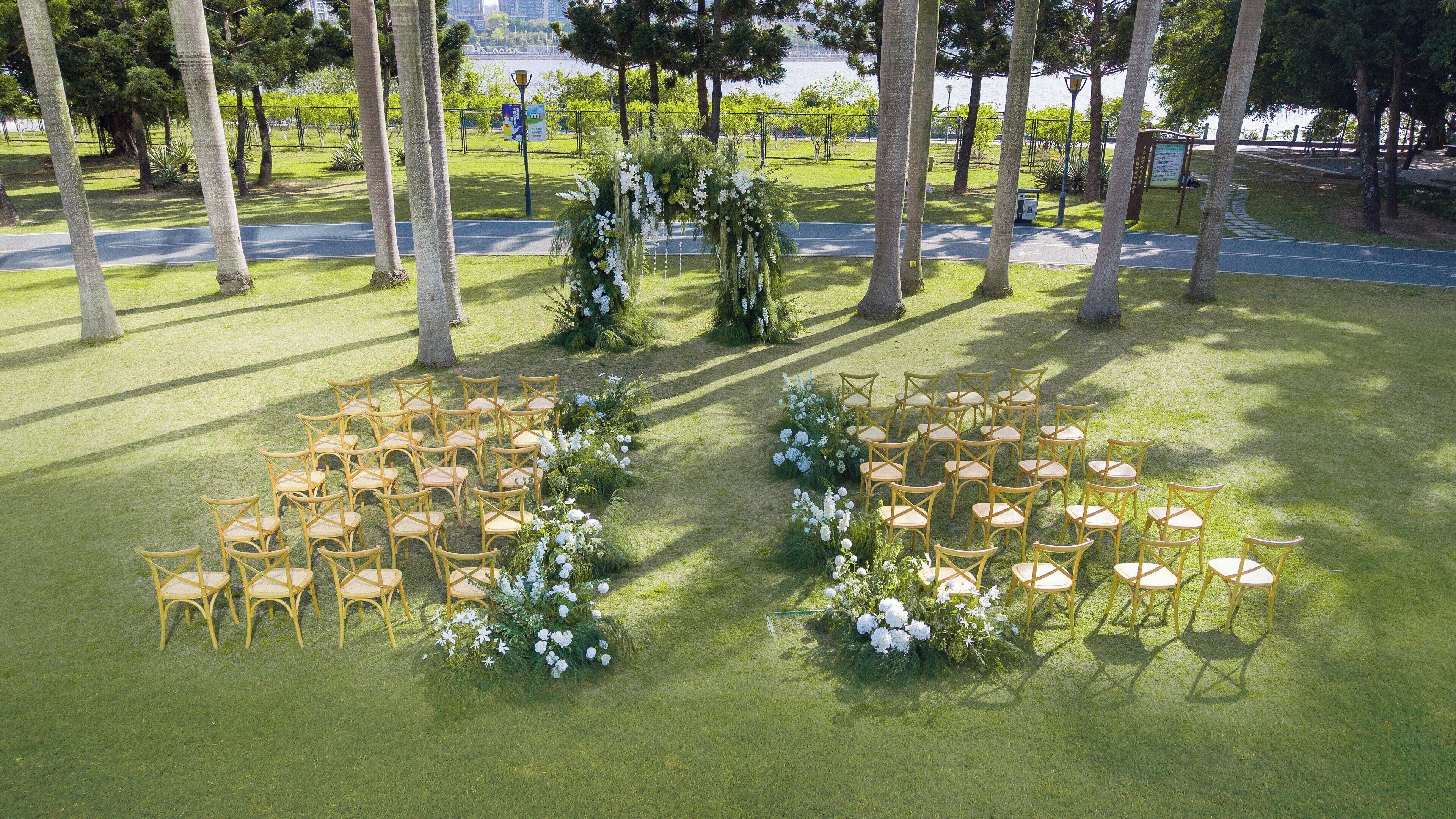 An outdoor wedding venue with rows of chairs and floral arrangements.