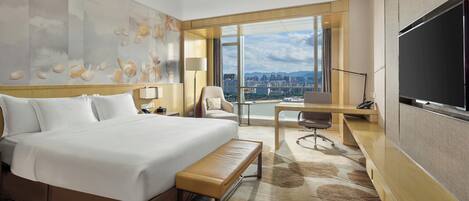 A hotel room with a large bed, a desk, a chair, and a TV.