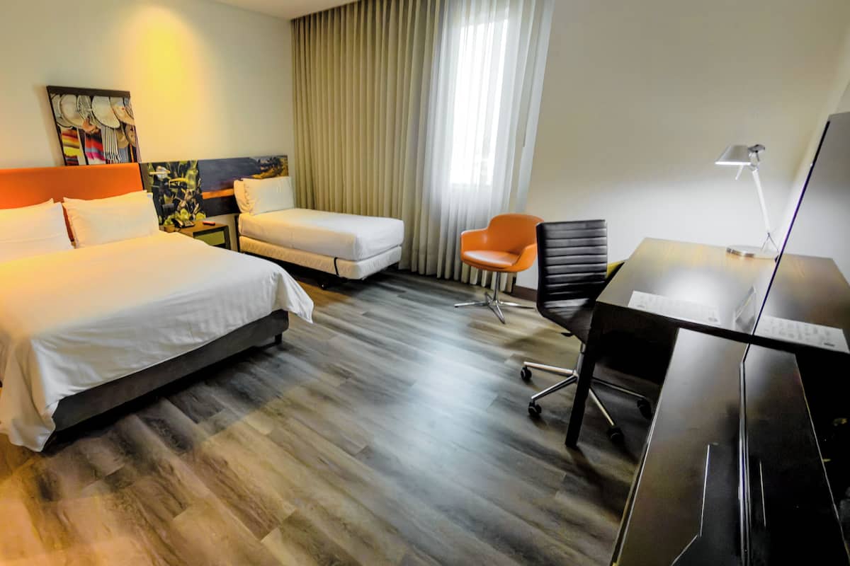 Una habitación de hotel con dos camas, un escritorio, una silla y un televisor.