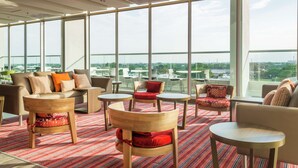 Amplia sala de estar con diversas opciones de asientos, grandes ventanales que ofrecen vistas a la ciudad y una decoración interior moderna.