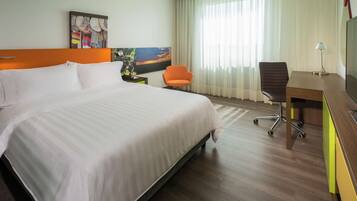 Een hotelkamer met een groot bed, een bureau, een oranje stoel en een schilderij aan de muur.