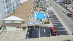 A hotel with a swimming pool, multiple parking spaces, and a view of the beach. - Pyramid Resort Motel (Wildwood Crest)