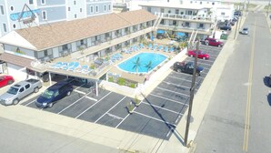 A hotel with a swimming pool, multiple floors, and a parking lot. - Pyramid Resort Motel (Wildwood Crest)