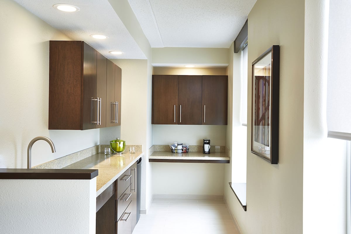 A modern kitchen with dark wooden cabinets, stainless steel appliances, and a light-colored countertop.