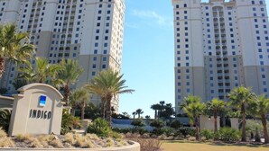 A high-rise hotel with multiple balconies, palm trees, and a sign labeled "INDIGO". - Indigo by Luxury Coastal Vacations (Pensacola)