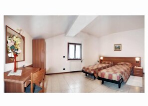 A bedroom with two beds, a desk, and a chair. - Albergo Il Castellino (Darfo Boario Terme)