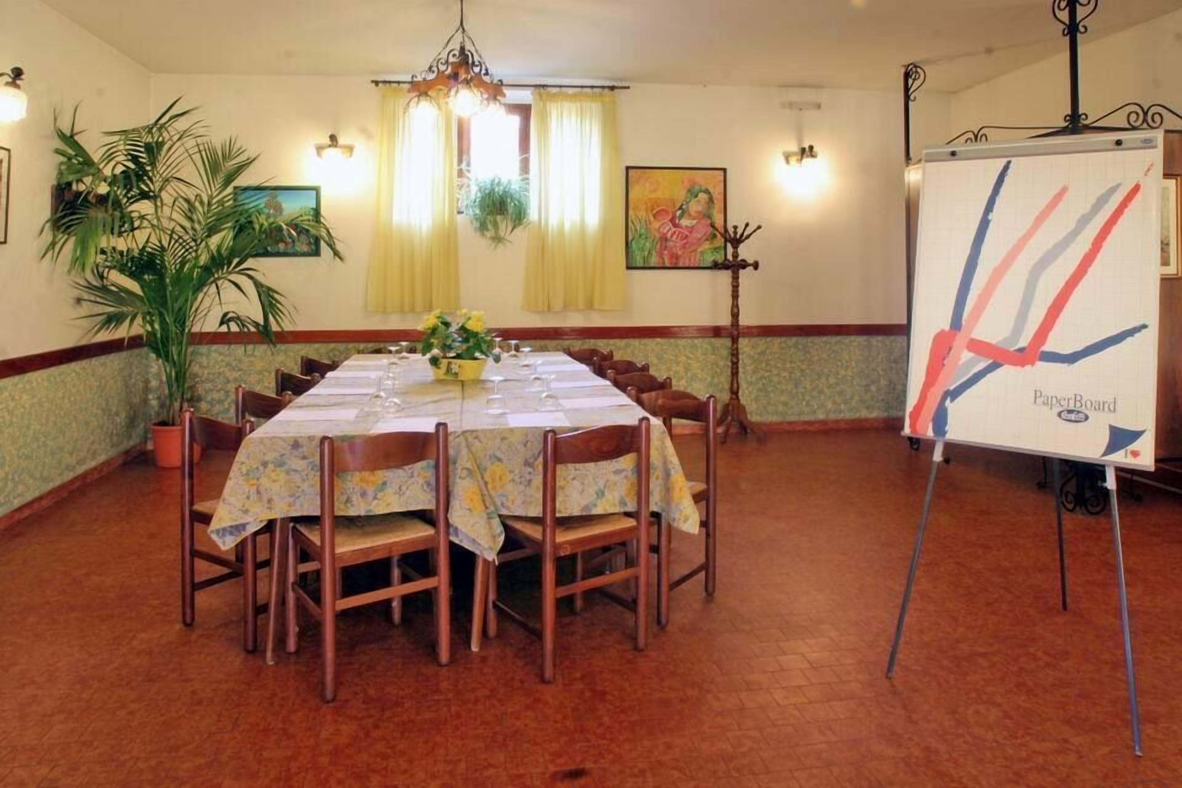 A conference room with a long table, chairs, a whiteboard, and decorative plants.