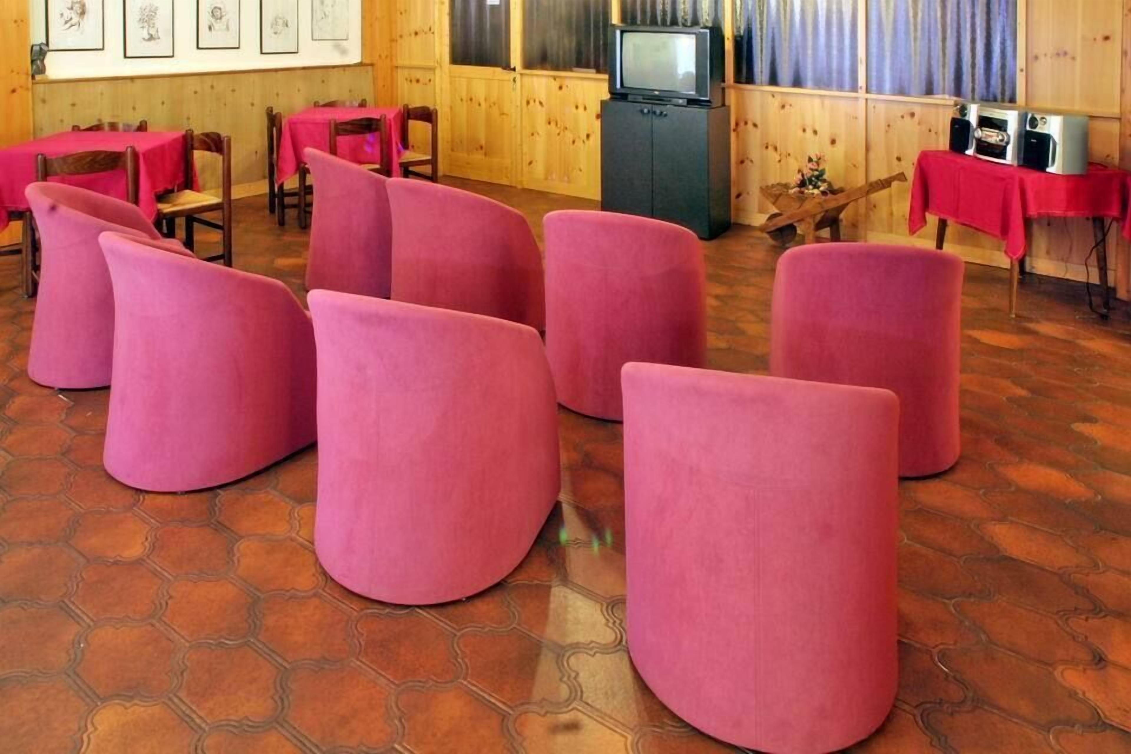A room with hexagonal patterned flooring, wooden walls, and pink cushioned seating.