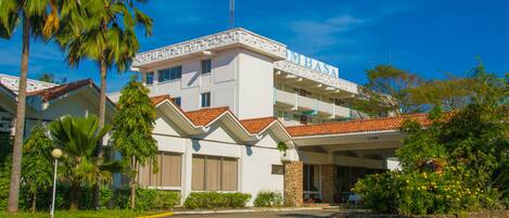 A hotel with a white facade, red-tiled roof, and a central entrance.