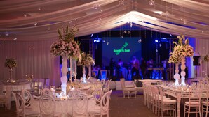 Un salón de banquetes con mesas y sillas redondas, decorado con centros de mesa florales y velas.