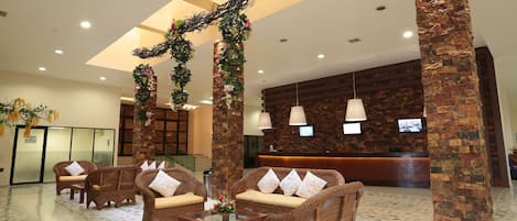 A lobby with wicker furniture, a reception desk, and a stone pillar.