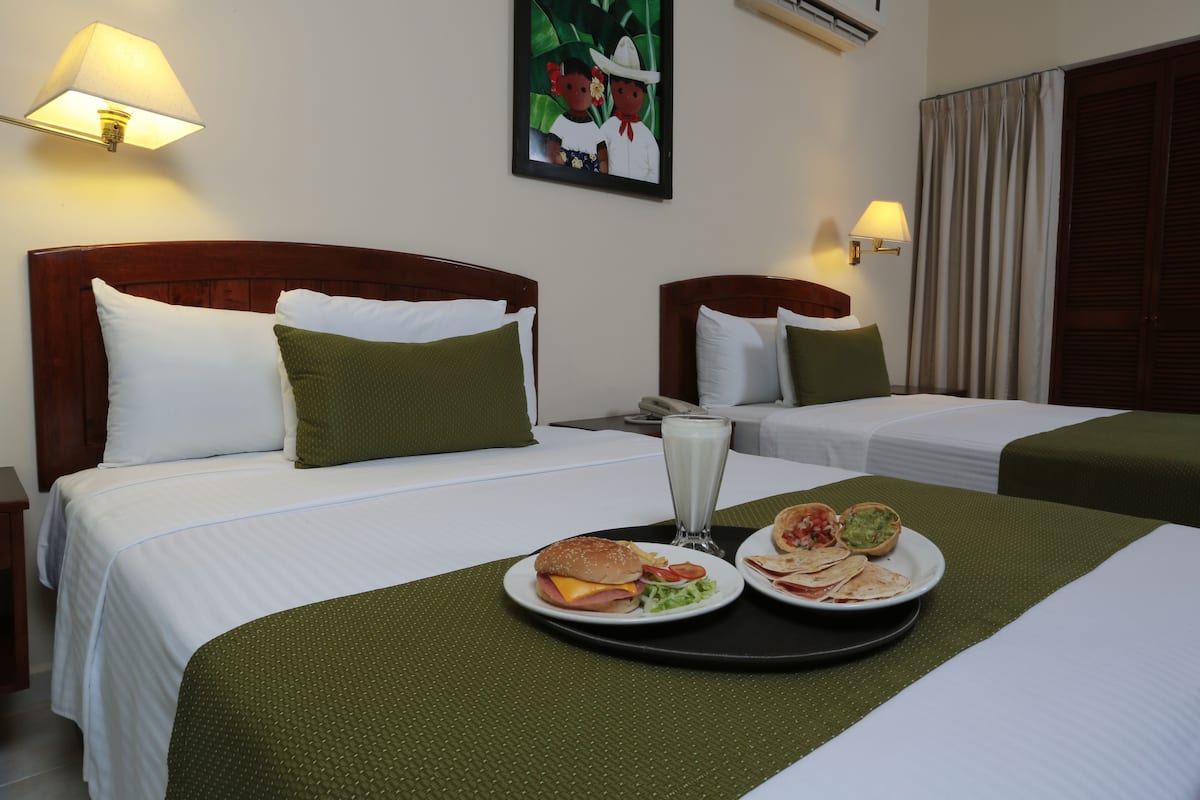 A hotel room with two beds, a tray with breakfast, and a painting on the wall.