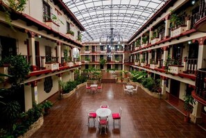 Un amplio atrio con techo alto, varios balcones y plantas en macetas.