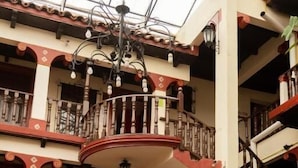 A multi-level atrium with a central staircase, balconies, and potted plants. - Hotel D' Monica  (San Cristóbal de las Casas)