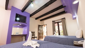 A hotel room with two beds, a TV, a desk, and a window with curtains. - Hotel D' Monica  (San Cristóbal de las Casas)