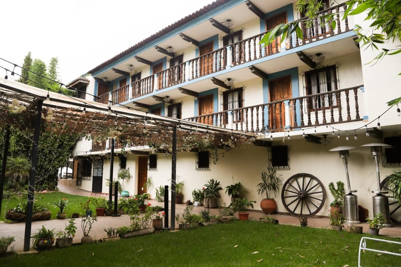 Un bâtiment à deux étages doté de balcons, une cour intérieure agrémentée de plantes en pot et une grande structure en forme de roue.
