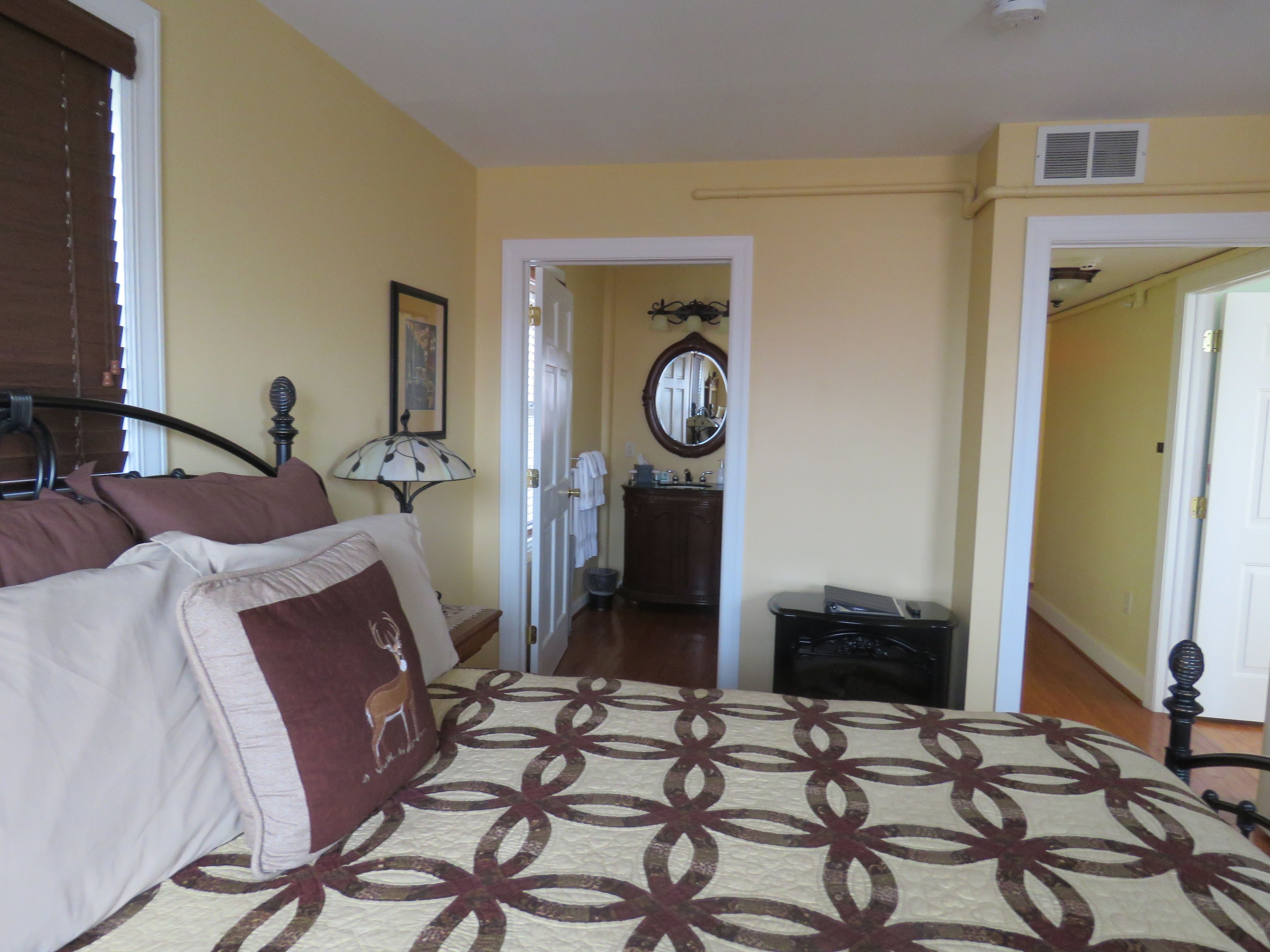 A bedroom with a bed, a nightstand, a lamp, and a dresser.