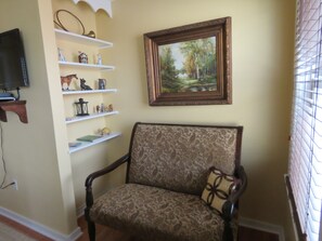 A living room with a patterned armchair, a painting on the wall, and shelves with various decorative items. - The Swope Manor Bed & Breakfast (Gettysburg)