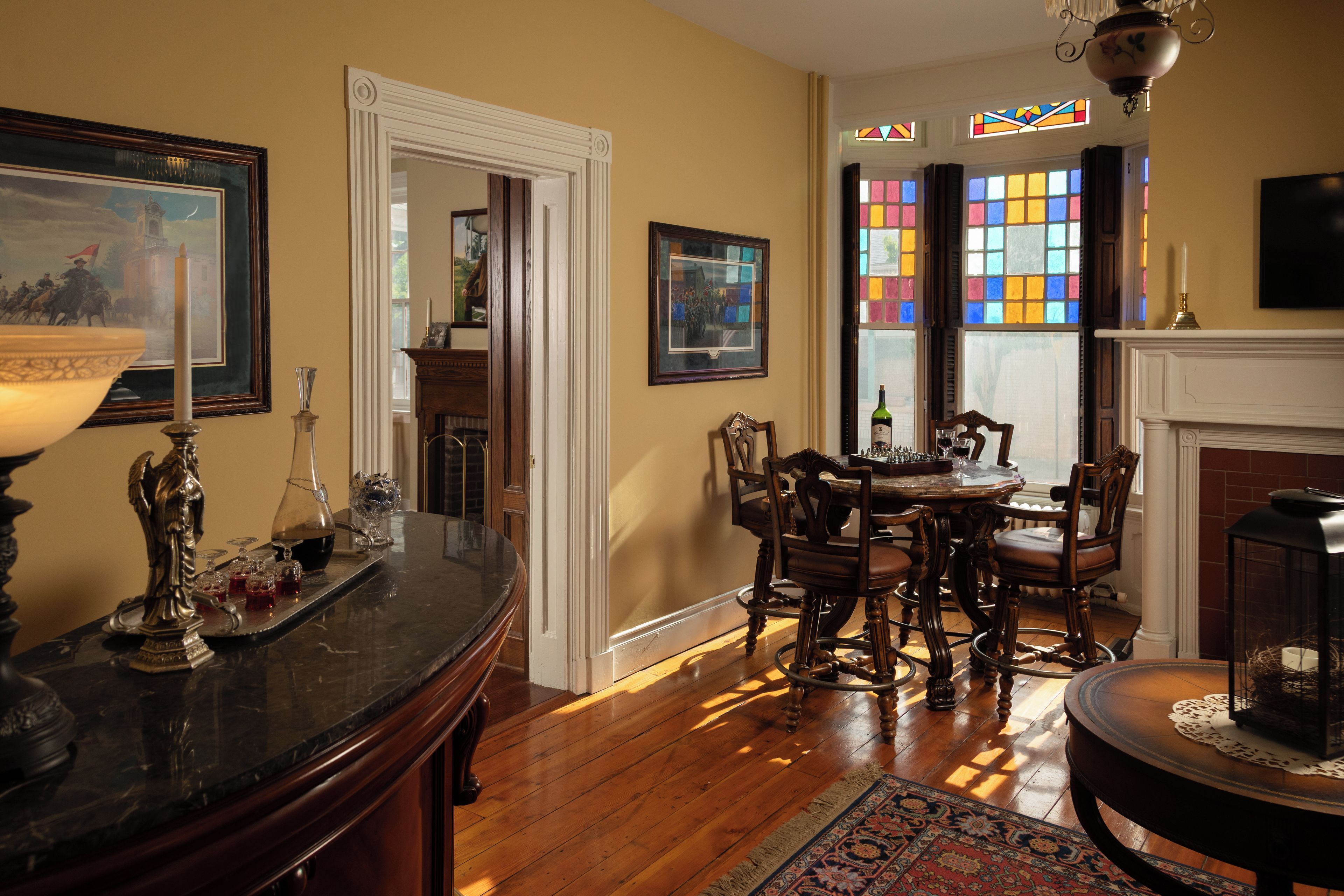 A dining area with a wooden table and chairs, a chandelier, and a fireplace.