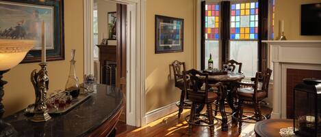 A dining area with a wooden table and chairs, a chandelier, and a fireplace.