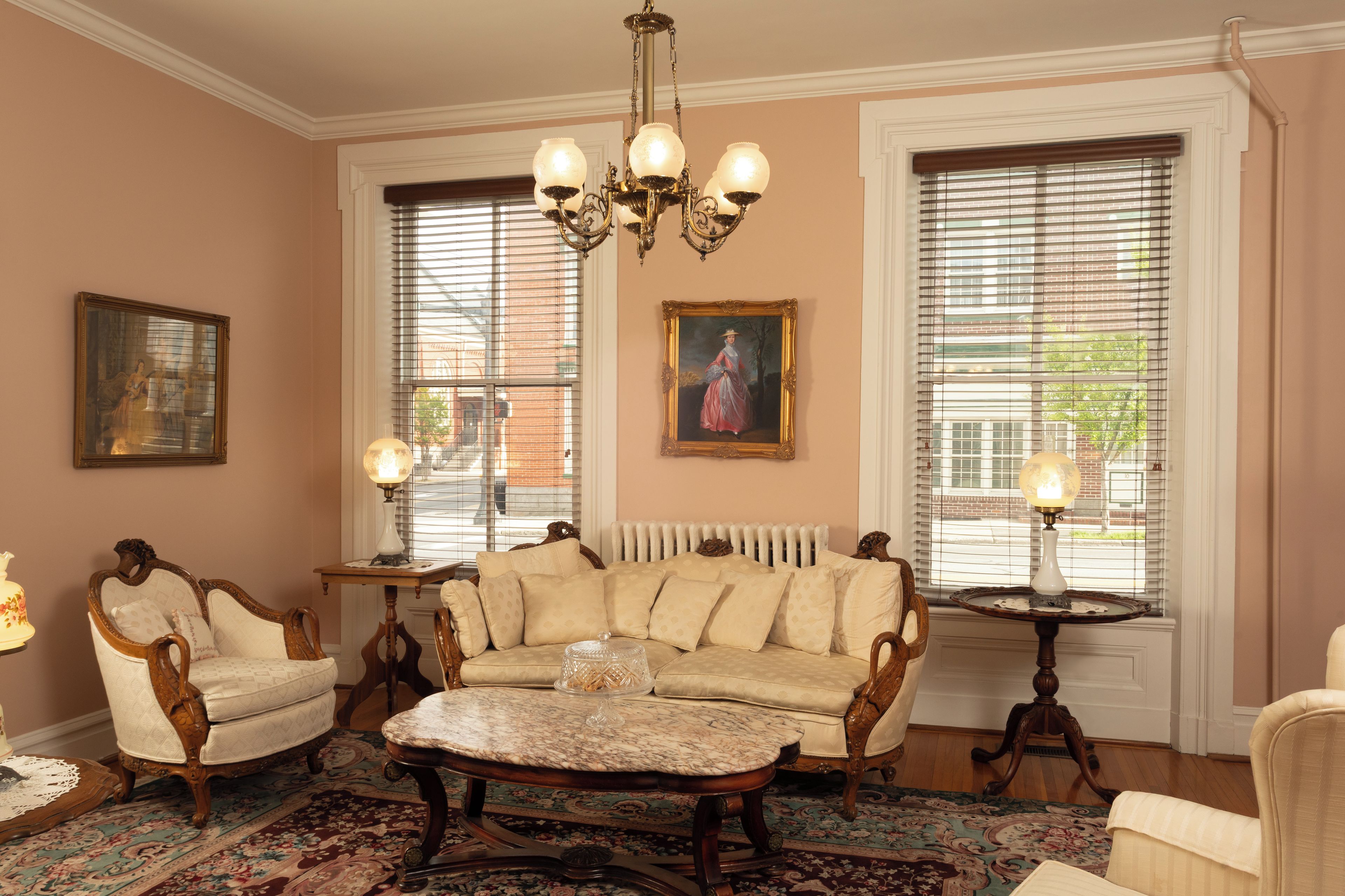 A room with a classic design, featuring a sofa, armchairs, a coffee table, and a chandelier.