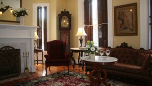 A traditional room with a fireplace, a red armchair, a round table with a vase of flowers, and a large painting on the wall. - The Swope Manor Bed & Breakfast (Gettysburg)