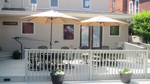 A guest entrance with a white fence, outdoor seating with umbrellas, and a painting on the wall. - The Swope Manor Bed & Breakfast (Gettysburg)