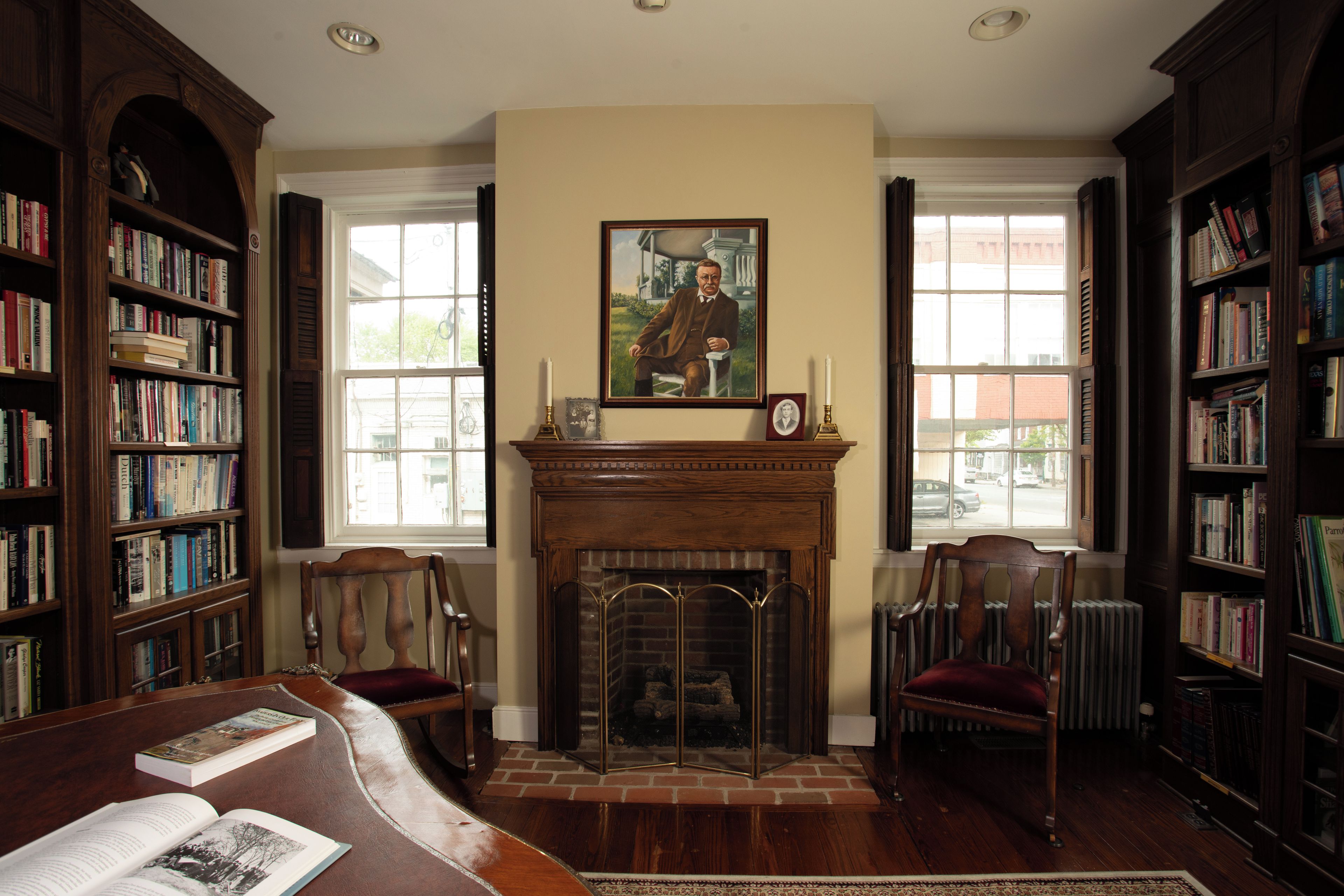 A library with bookshelves, a fireplace, and a portrait on the wall.