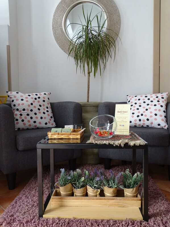Una sala de estar con un sofá gris, un espejo redondo, una mesita con un cuenco de vidrio y una planta en maceta.
