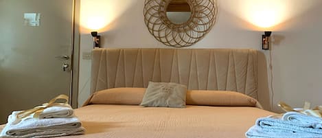 A neatly made bed with a quilted cover, a pillow, and folded towels on either side.