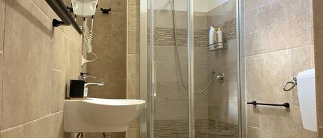A modern bathroom with a glass-enclosed shower, a pedestal sink, and a toilet.
