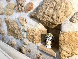 Ένας πέτρινος τοίχος με ένα ράφι όπου είναι τοποθετημένο ένα κεραμικό γλυπτό.