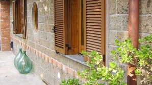 A stone building with wooden shutters on windows and a green vase on the ground. - Casale Nunziatina (Sorrento)