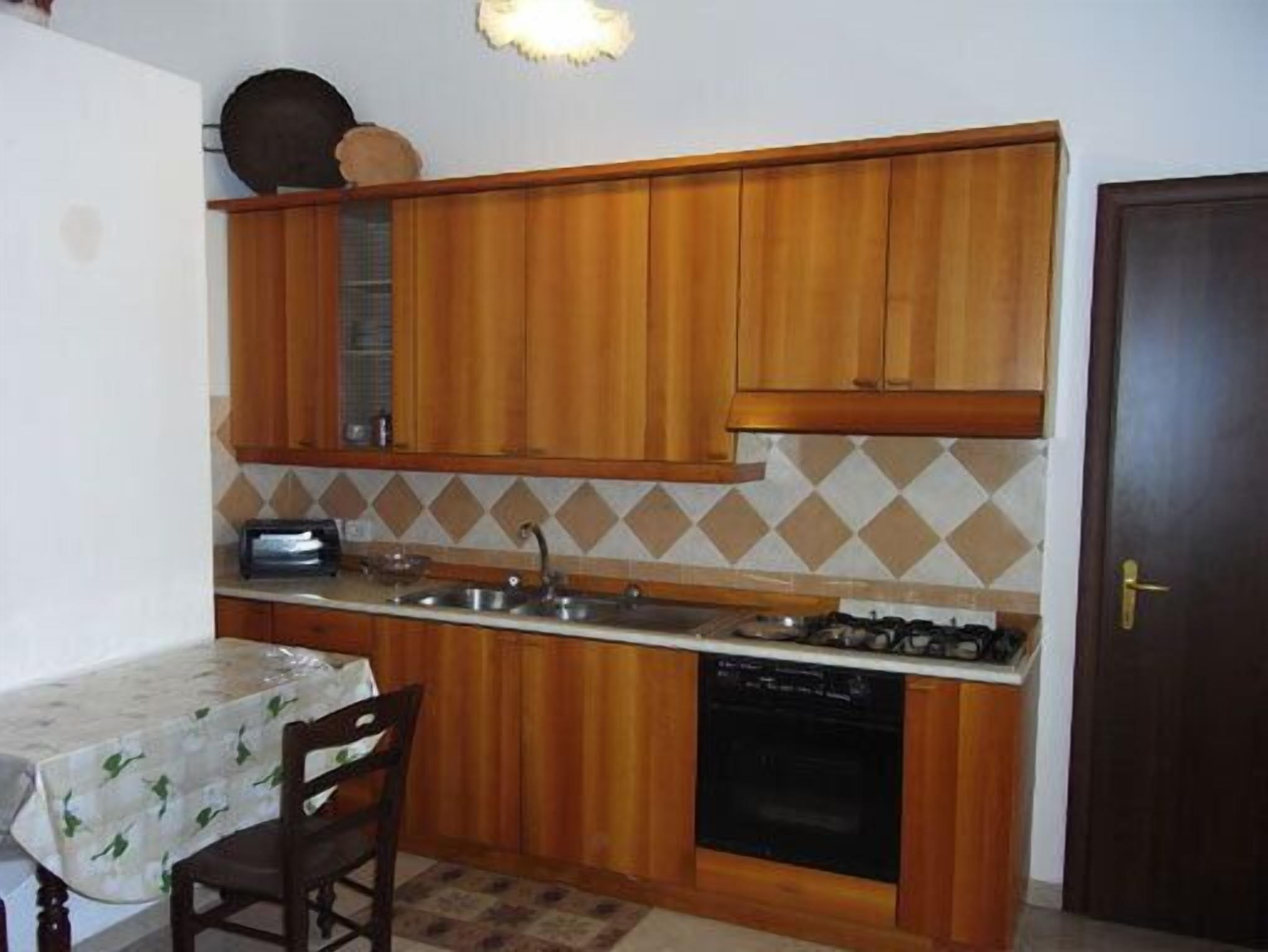 Une cuisine compacte avec des meubles en bois, une cuisinière à gaz, un évier et un lave-vaisselle.