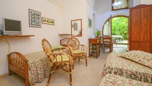 A cozy room with a bed, two chairs, a small table, and a TV. - Casale Nunziatina (Sorrento)