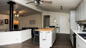 Une cuisine moderne dotée d’un îlot central, de meubles blancs et d’un ventilateur de plafond.