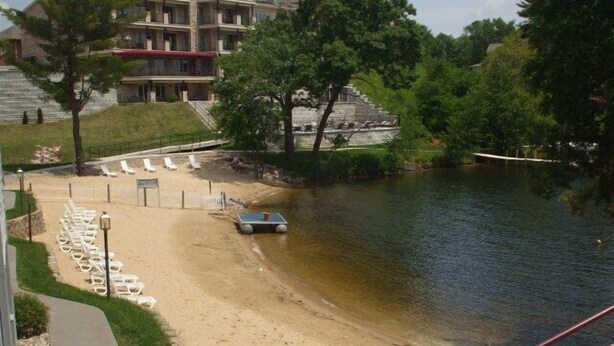 Une plage avec des chaises longues, un petit bateau et un bâtiment en arrière-plan.