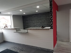 A reception area with a stone wall, a marble counter, and a red accent wall. - Red Carpet Inn Rochester (Rochester)