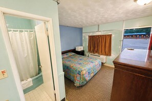 Habitación de motel con cama, escritorio, ventana y puerta.