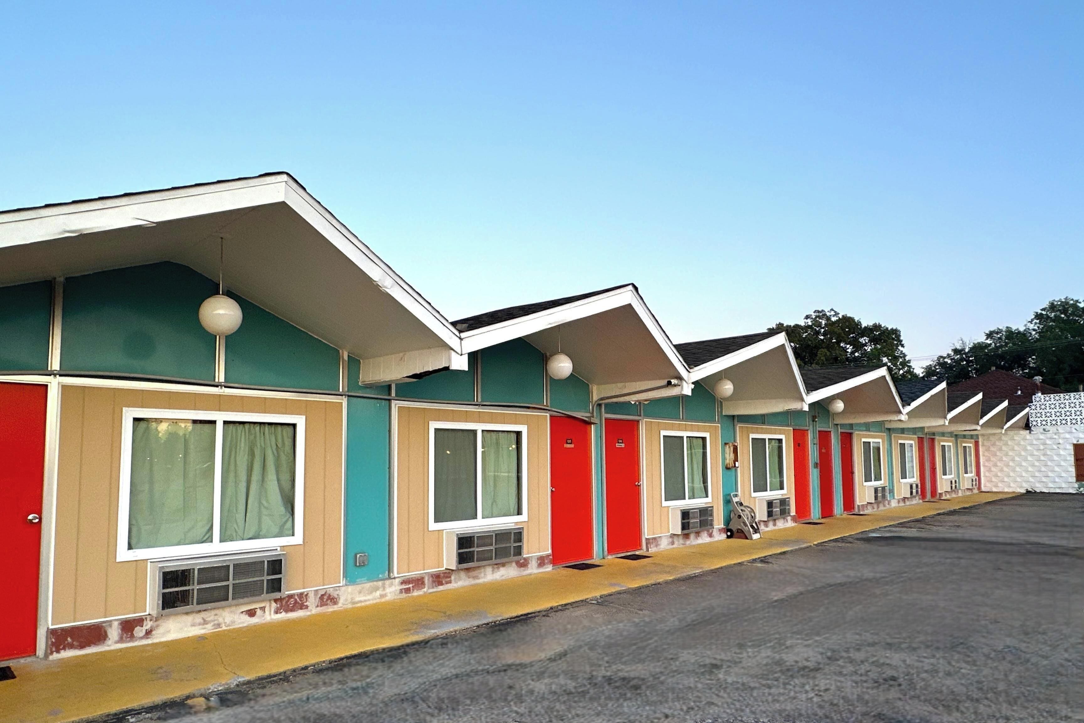 Eine Reihe von Motelgebäuden mit separaten Zimmern, jedes mit einem Fenster und einer Tür.