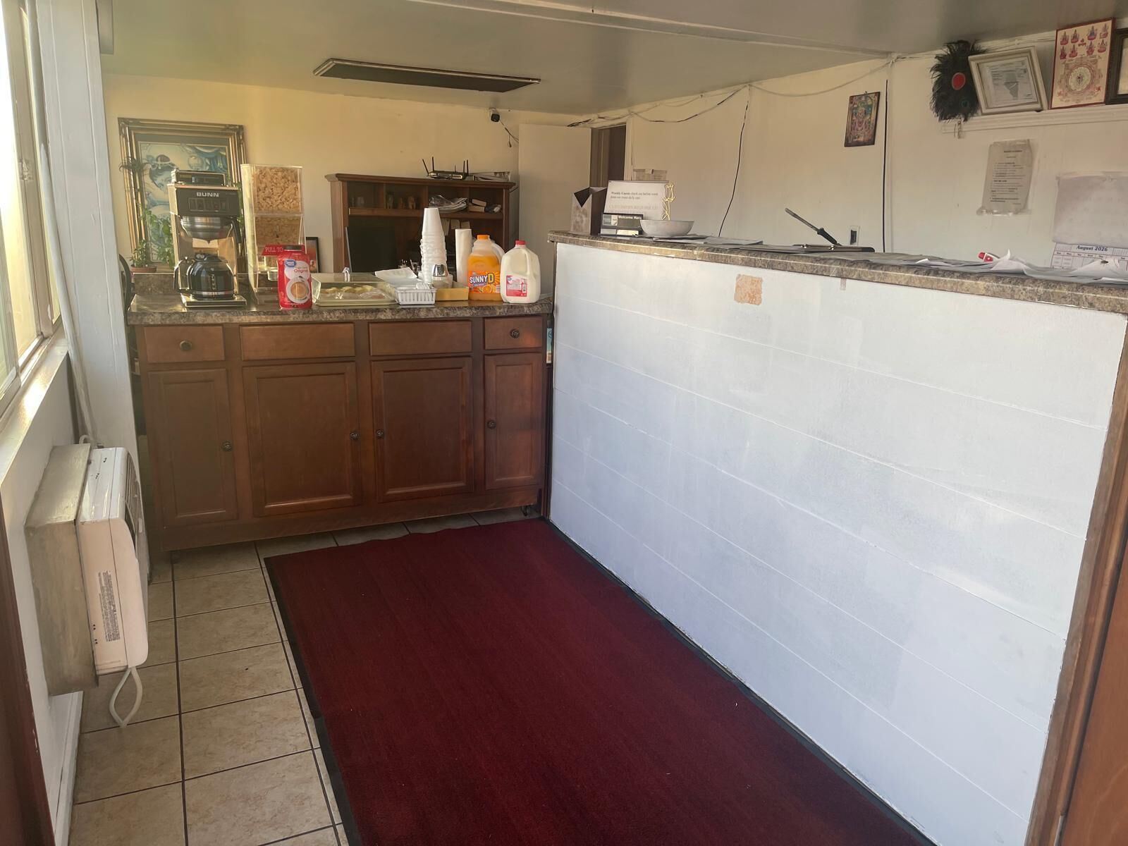 A kitchen with wooden cabinets, a countertop, and a red rug.